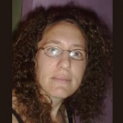 Woman with long dark curly hair and glasses